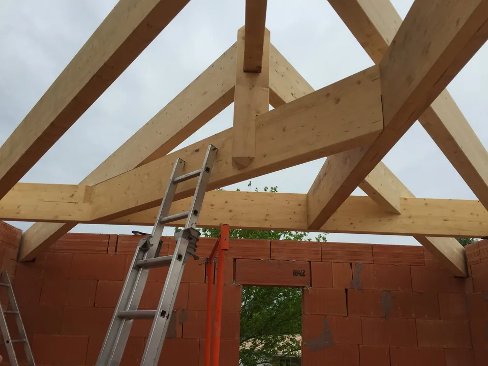 Assemblages d’une charpente en bois en cours de construction, vus depuis l’intérieur.