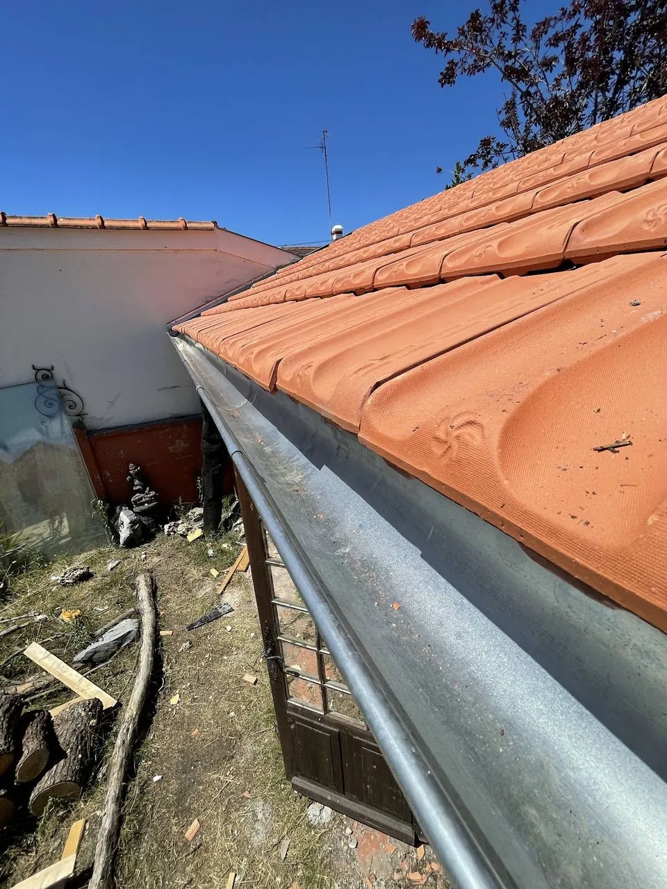 Vue rapprochée d’une couverture en tuiles et de sa gouttière métallique.
